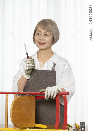 リビングで趣味のDIYで椅子を作るシニア女性 143658023