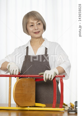 リビングで趣味のDIYで椅子を作るシニア女性 143658028