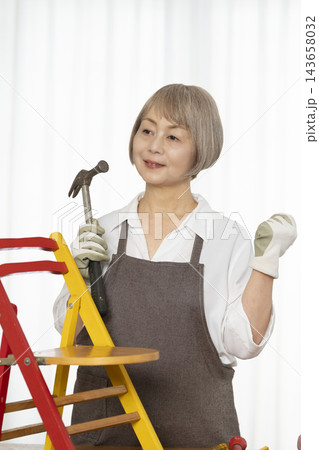 リビングで趣味のDIYで椅子を作るシニア女性 リビングで趣味のDIYで椅子を作るシニア女性 143658032