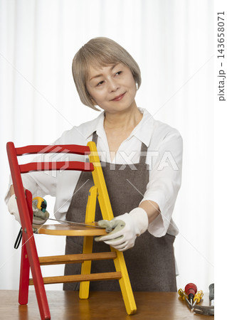 リビングで趣味のDIYで椅子を作るシニア女性 リビングで趣味のDIYで椅子を作るシニア女性 143658071