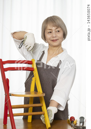 リビングで趣味のDIYで椅子を作るシニア女性 リビングで趣味のDIYで椅子を作るシニア女性 143658074
