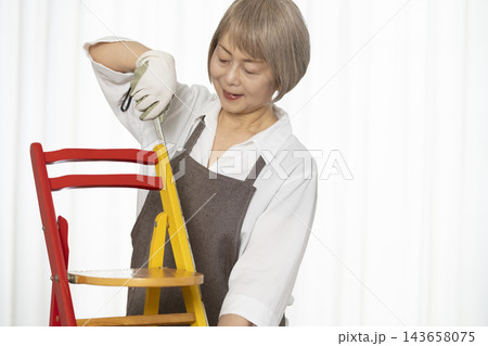 リビングで趣味のDIYで椅子を作るシニア女性 リビングで趣味のDIYで椅子を作るシニア女性 143658075
