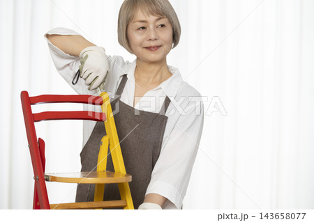 リビングで趣味のDIYで椅子を作るシニア女性 リビングで趣味のDIYで椅子を作るシニア女性 143658077