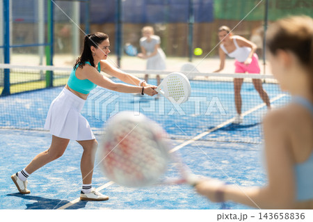 Woman playing with other paddle tennis players 143658836