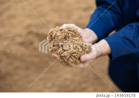 Hands of male farmworker holding handful of brewers grains Hands of male farmworker holding handful of brewers grains 143659178