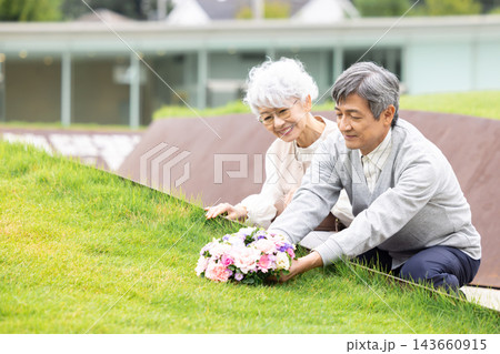 樹木葬　樹木葬墓地で花を手向けるシニア夫婦 143660915