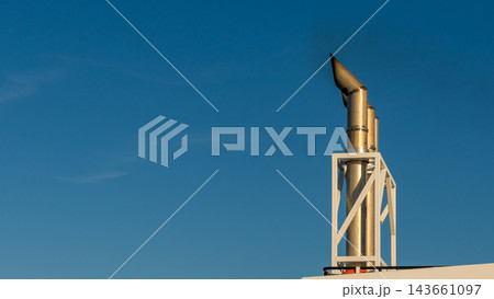 Ferry funnel and structural framework rising against a clear blue sky in warm sunlight, viewed as a close architectural detail 143661097