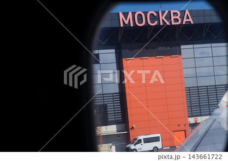 View from airplane window showing Moscow airport terminal with prominent signage, modern design, and a vehicle parked in front of the building View from airplane window showing Moscow airport terminal with prominent signage, modern design, and a vehicle parked in front of the building 143661722