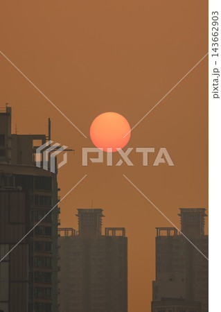 Hong Kong Oct 13 2026 Glowing Crimson Sun Setting Between High Rise Skyscrapers Hong Kong Oct 13 2026 Glowing Crimson Sun Setting Between High Rise Skyscrapers 143662903