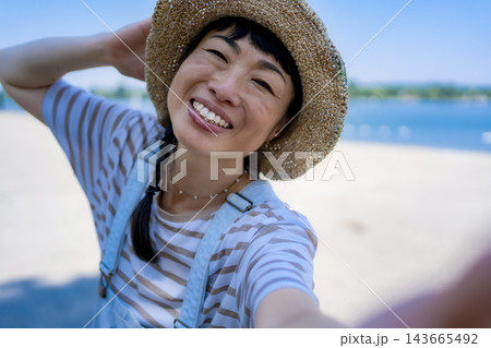 Young adult asian woman enjoying summer beach selfie 143665492
