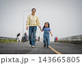 mother and preschool child girl holding hand and walking on a road on mountain in morning 143665805