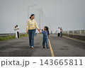 mother and preschool child girl holding hand and walking on a road on mountain in morning 143665811