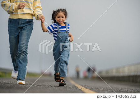 mother and preschool child girl holding hand and running on a road on mountain in morning mother and preschool child girl holding hand and running on a road on mountain in morning 143665812