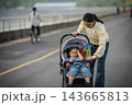 mother adjusting stroller shade for sleepy or headache little daughter outdoors on road 143665813