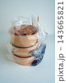 Three brown kraft paper takeout food bowls with clear lids inside a plastic bag on a white background. Includes chopsticks and condiments for a meal delivery or restaurant packaging concept. 143665821