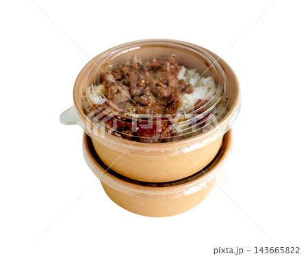 Two stacked kraft paper bowls with clear plastic lids containing grilled meat over white rice. Sustainable food packaging for takeaway or delivery isolated on a white background. 143665822