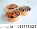 Three round kraft paper bowls with clear lids containing fried chicken over rice, shown on a neutral white background. Ideal for food delivery and restaurant packaging concepts. 143665824