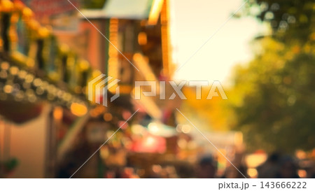 Blurred background of busy outdoor street festival market with lights and crowds in sunlight Blurred background of busy outdoor street festival market with lights and crowds in sunlight 143666222