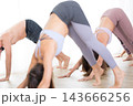 Group of young sporty active poeple in yoga studio, practicing yoga lesson with instructor, practicing Adho mukha svanasana downward dog asana pose. Healthy active lifestyle, working out in gym. 143666256