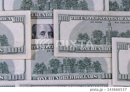 Benjamin Franklin's eyes peeking through scattered hundred dollar bills. Benjamin Franklin's eyes peeking through scattered hundred dollar bills. 143666537