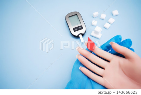Diabetes concept with blood glucose meter, sugar cubes, blue awareness ribbon and medical gloves on blue background 143666625