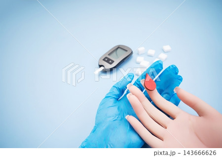 Diabetes concept with blood glucose meter, sugar cubes, blue awareness ribbon and medical gloves on blue background Diabetes concept with blood glucose meter, sugar cubes, blue awareness ribbon and medical gloves on blue background 143666626