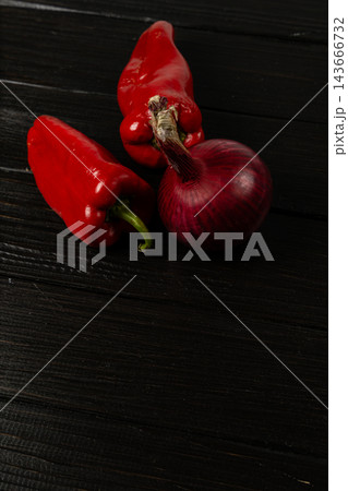 Red peppers and onion arranged on a dark kitchen surface 143666732