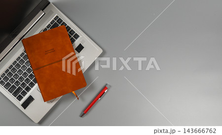 Laptop with a notebook and pen on a gray desk during work hours Laptop with a notebook and pen on a gray desk during work hours 143666762