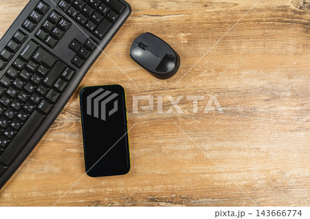 Office workspace with keyboard, mouse, and smartphone on wooden desk Office workspace with keyboard, mouse, and smartphone on wooden desk 143666774