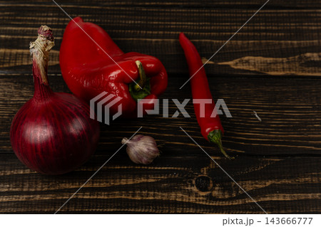 Pepper, chili, onion, and garlic arranged on a wooden kitchen surface Pepper, chili, onion, and garlic arranged on a wooden kitchen surface 143666777