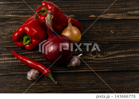 Peppers, chili, onion, and garlic on a wooden kitchen surface 143666778