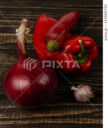 Peppers, onion, and garlic arranged on a wooden surface Peppers, onion, and garlic arranged on a wooden surface 143666780