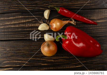 Peppers, onions, and garlic arranged on a wooden table Peppers, onions, and garlic arranged on a wooden table 143666781
