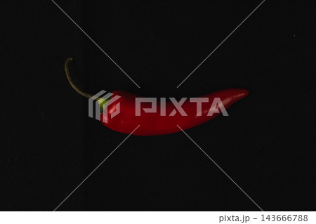 Red chili pepper rests against a black background Red chili pepper rests against a black background 143666788
