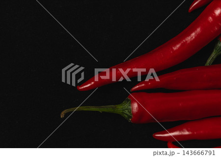 Red chili peppers arranged against a black background Red chili peppers arranged against a black background 143666791