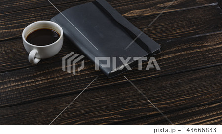 Coffee cup and notebook on a wooden desk during a work break 143666833