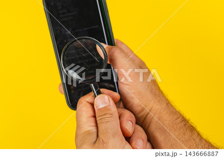 Using a magnifying glass to inspect a smartphone screen Using a magnifying glass to inspect a smartphone screen 143666887