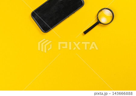 Smartphone and magnifying glass on yellow background for investigation Smartphone and magnifying glass on yellow background for investigation 143666888