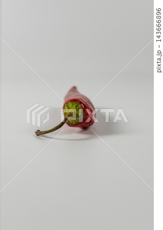 Red chili pepper resting on a white surface in a studio 143666896