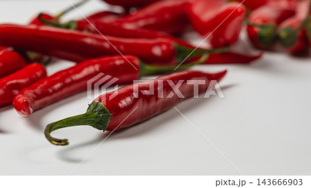 Red chili peppers arranged on a white surface for cooking 143666903