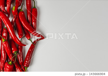 Red chili peppers arranged along the left side on white Red chili peppers arranged along the left side on white 143666904