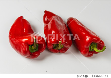 Red sweet peppers arranged on a white surface for cooking 143666934