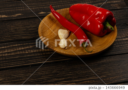 Red pepper, chili, and garlic on a wooden plate in a kitchen 143666949