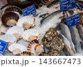 Fresh scallops, oysters and sea bass on ice at a food market 143667473