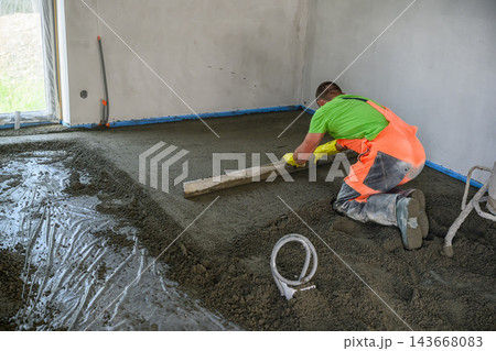 Construction Worker Pouring and Leveling Concrete Screed Floor Indoors 143668083