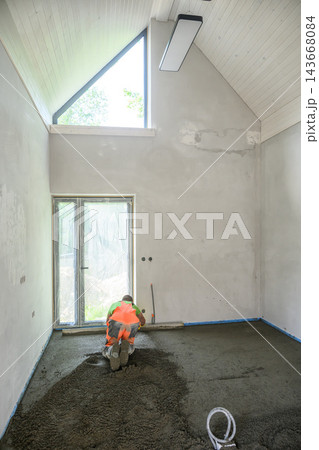 Construction Worker Pouring and Leveling Concrete Screed Floor Indoors 143668084