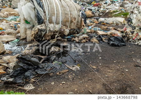 Mountains of trash create a grim landscape, with black bags and debris scattered across a landfill, showing the impact of pollution Mountains of trash create a grim landscape, with black bags and debris scattered across a landfill, showing the impact of pollution 143668798