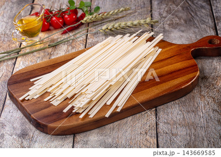 Udon noodles on wooden cutting board with cherry tomatoes and olive oil 143669585