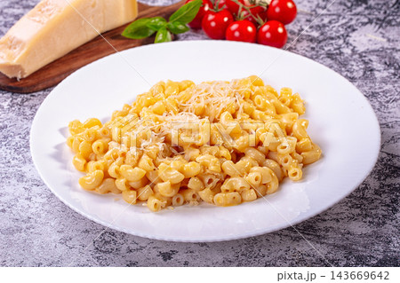 Creamy macaroni and cheese on white plate with parmesan and cherry tomatoes Creamy macaroni and cheese on white plate with parmesan and cherry tomatoes 143669642