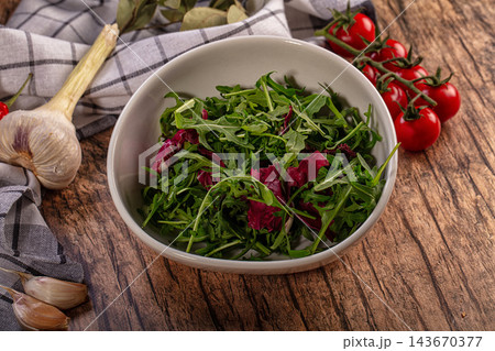 Fresh garlic bulbs and cherry tomatoes on vine beside ceramic bowl of arugula and radicchio leaves on rustic wood, healthy salad ingredients Fresh garlic bulbs and cherry tomatoes on vine beside ceramic bowl of arugula and radicchio leaves on rustic wood, healthy salad ingredients 143670377